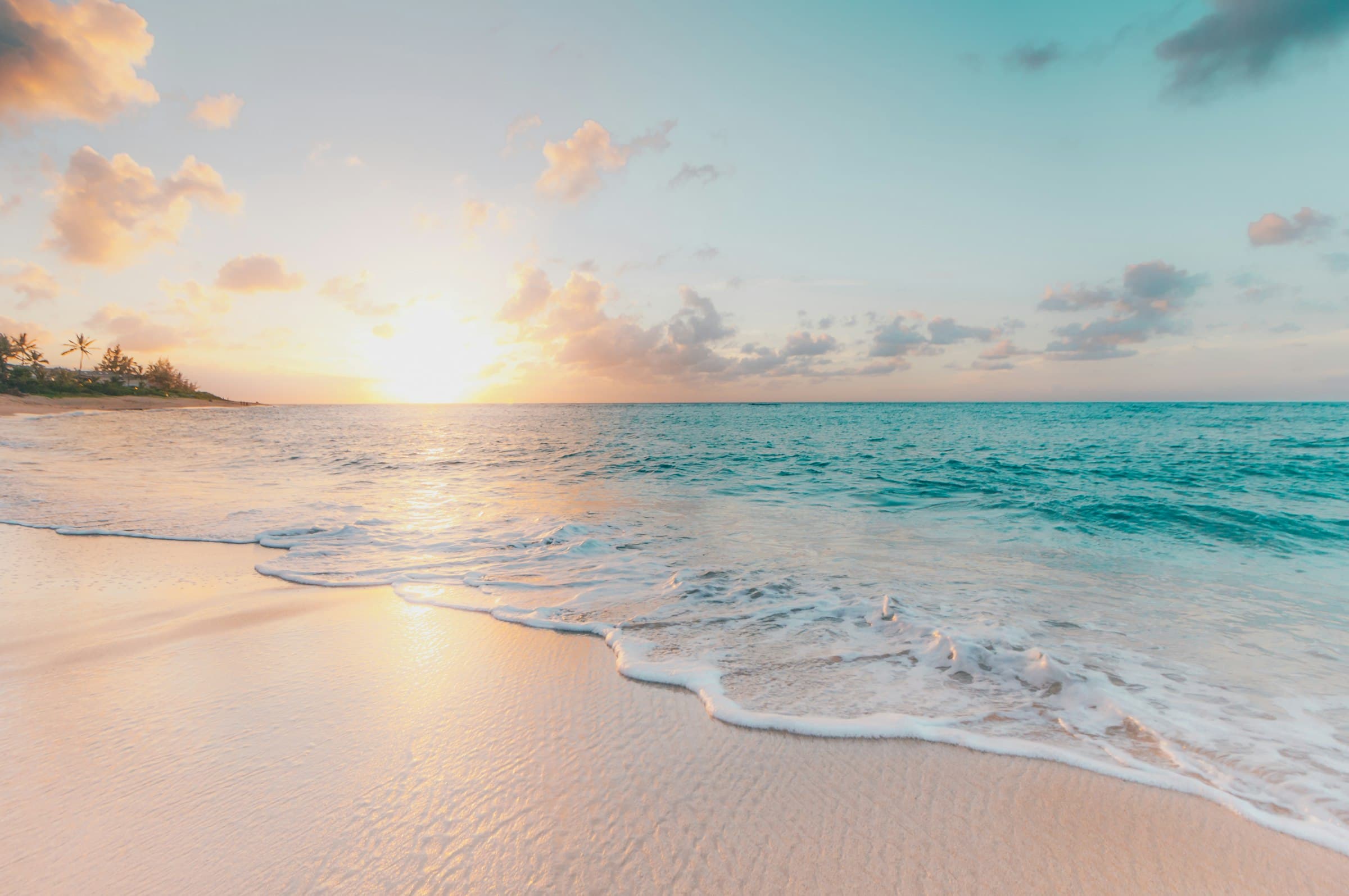 Soft waves washing onto a wide beach at sunset